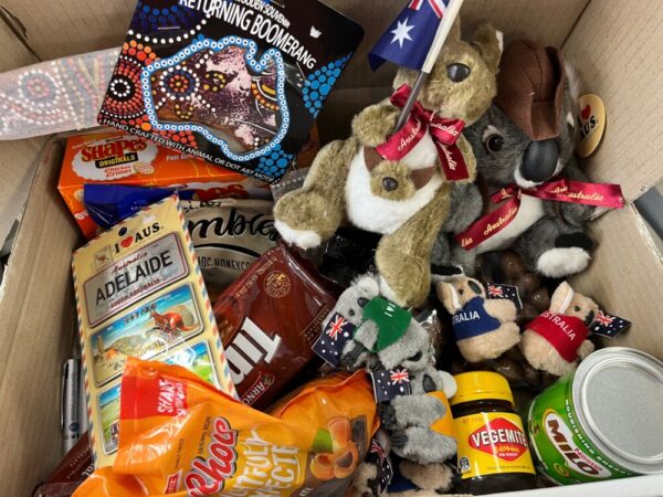 箱の中にお菓子やオーストラリアの旗を持ったぬいぐるみが詰め込まれている